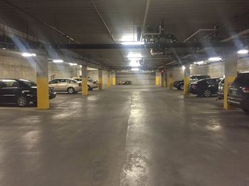 A parking garage with yellow pillars and cars parked in it